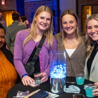 Four girls stand around a table with juice.